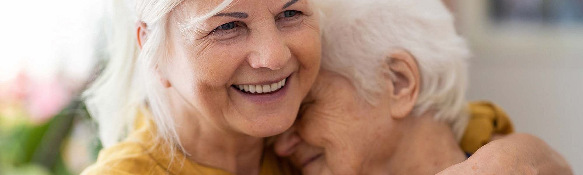 Eine Frau hält eine ältere Frau im Arm und lächelt